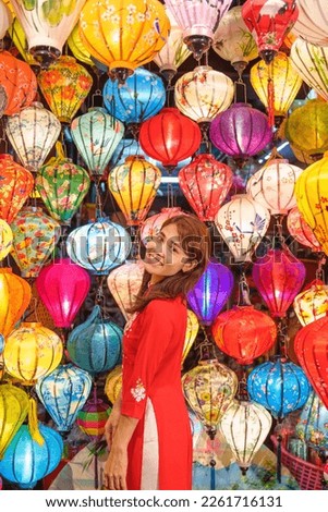 happy woman wearing Ao Dai Vietnamese dress with colorful lanterns, traveler sightseeing at Hoi An ancient town in central Vietnam.landmark for tourist attractions.Vietnam and Southeast travel concept Royalty-Free Stock Photo #2261716131