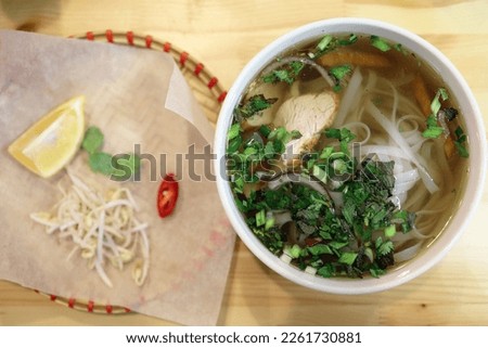 Vietnamese pho soup in a cafe, served with sprouted wheat and chili pepper