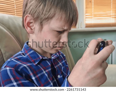 Teenager child with poor eyesight squints and looks at screen. Hyperopia myopia astigmatism glaucoma and addiction to gadgets concept Royalty-Free Stock Photo #2261731143