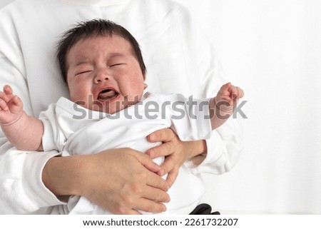 A crying baby being held by his mother on his lap (0 years and 2 months, Japanese, boy)