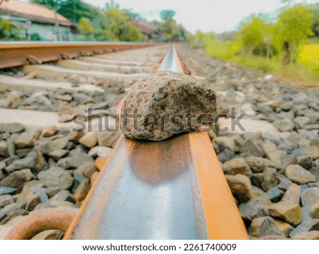 a stone set on a railroad track that is slightly rusty during the day.