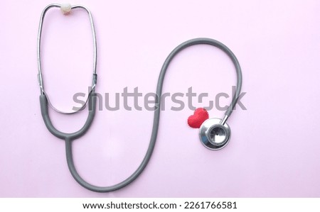 flat lay a red heart gray stethoscope isolate on a pink doctor table.minimalist trend. love and valentines day concept