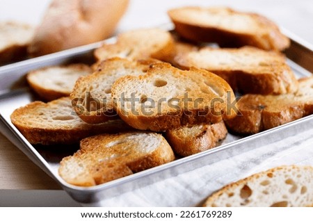 Crostini, Crusty baguette slices toasted with olive oil, on a baking tray. Closeup. Royalty-Free Stock Photo #2261769289