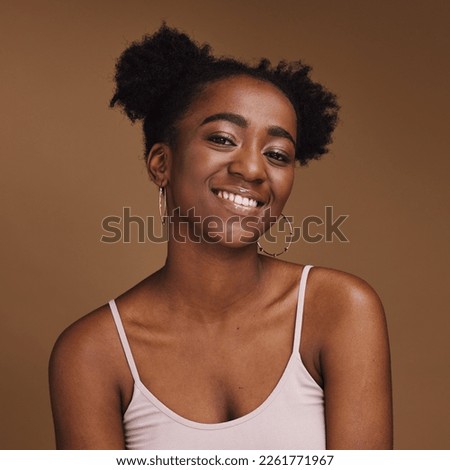 Black woman, smile and student portrait of a gen z person with makeup and jewelry in a studio. Isolated, brown background and happiness of a young female with skincare glow, cosmetics and face Royalty-Free Stock Photo #2261771967