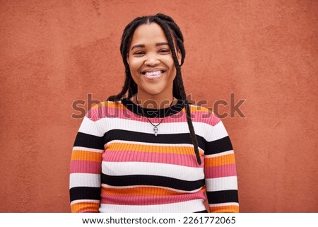 Portrait, fashion and braids with a black woman on an orange background outdoor for style or empowerment. Style, wellness and profile picture with an african american person posing against a wall