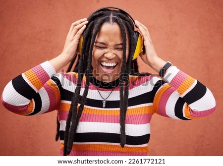 Black woman, music headphones and happiness by wall in city for walk, adventure and comedy album. Young gen z girl, audio streaming and listen to comic podcast on website, radio and happy in metro