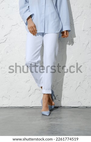 Female legs in white jeans blue shirt and stilettos