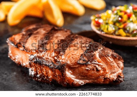 Succulent Farmhouse Rustic Rump Steak with Thyme Garnish shot against dark background with wood burner. The perfect image for your bistro or restaurant menu cover art. Copy space. Royalty-Free Stock Photo #2261774833