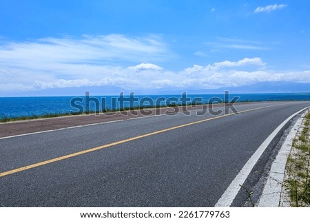 Asphalt road and lake with sky clouds natural scenery in Xinjiang, China. Royalty-Free Stock Photo #2261779763