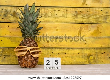 Creative planner calendar december with number  25. Pineapple character on bright yellow summer wooden background with calendar cubes.