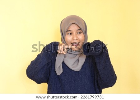 Various expressions of Asian women wearing hijabs, using navy sweaters against a yellow background