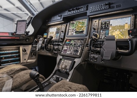 Aircraft interior, view into the cockpit of a modern turboprop aircraft with glass cockpit avionics. Focused selectively on the closer flying stick. Royalty-Free Stock Photo #2261799811