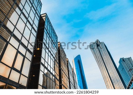 The skyscraper is reflected in the windows of the facade of a modern glass building