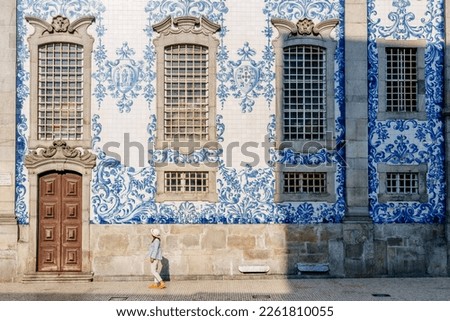 Tourist walking, azulejos tiles over Chapel Of Souls, Porto, Portugal Royalty-Free Stock Photo #2261810055
