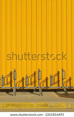 Vertical shot of bike parking near a bright yellow profiled metal wall, fence or warehouse idea, screen background or design articles