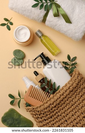 Compact toiletry bag with different cosmetic products, spa stones and towel on beige background, flat lay Royalty-Free Stock Photo #2261831105