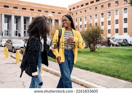 Stock photo of black students talking and laughing after class in college.