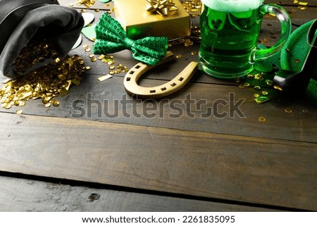 Image of green hat, green clover, horse shoe and copy space on wooden background. St patrick's day, irish tradition and celebration concept.