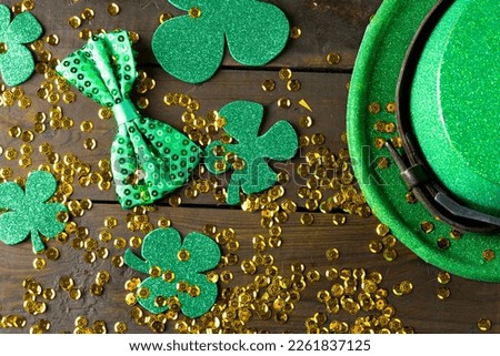 Image of green hat, green clover, green bow tie and gold sequins on wooden background. St patrick's day, irish tradition and celebration concept.
