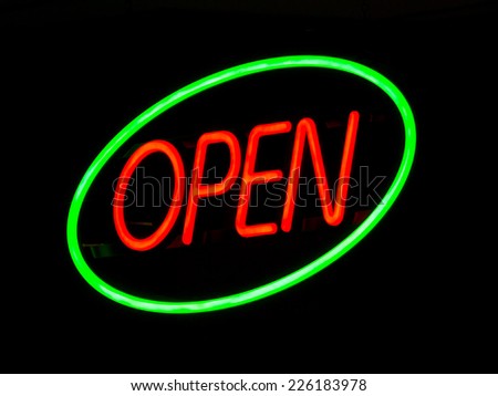 Illuminated neon open sign outside lit up at night on a shop window to advertise that the retail outlet is serving.