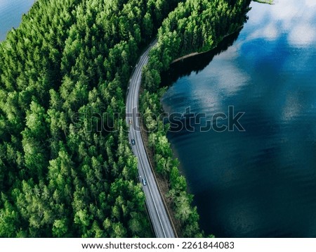 Aerial view of coastline road with green woods and blue lakes water in summer Finland.