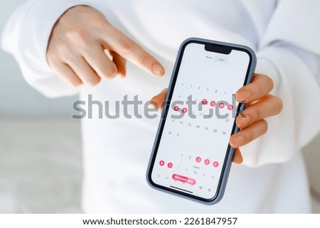 A women showing phone application to track the female cycle, ovulation, menstruation, periods.  Royalty-Free Stock Photo #2261847957