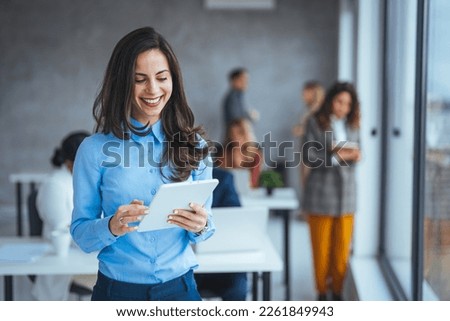 Urban happy business woman using tablet computer and working. Happy businesswoman using a digital tablet. Young leading businesswoman using a wireless tablet. Designer standing in her office 