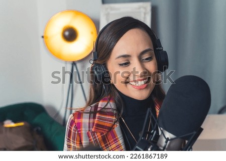 Female influencer recording video indoors for internet audience using microphone. High quality photo