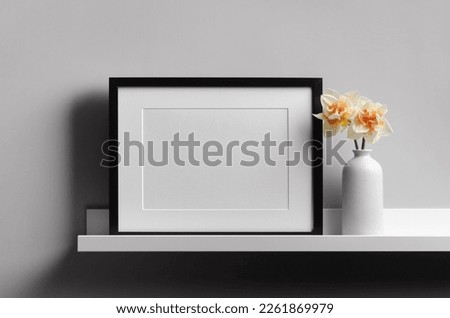 Blank landscape picture frame mockup on shelf with flowers, blank mockup with copy space