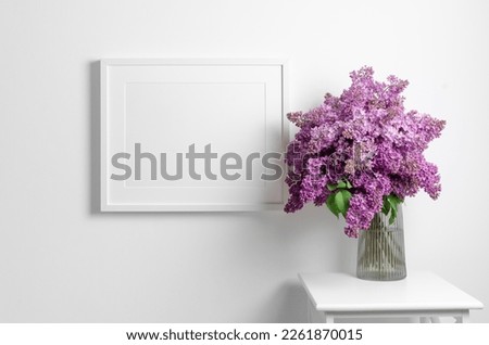 Landscape frame mockup on white wall with lilac flowers, blank mockup template with copy space
