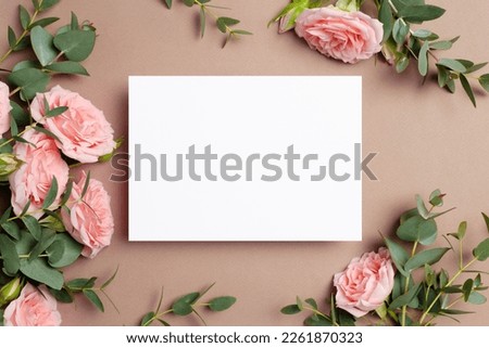 Wedding invitation or greeting card mockup with roses and eucalyptus flowers on beige background