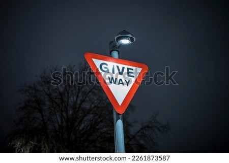 Give Way UK Road sign at night with blurred background
