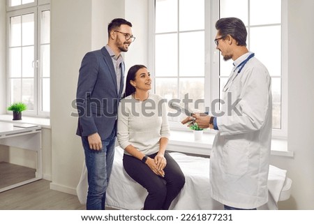 Happy married couple with family therapist. Young man and woman talking with their doctor and planning pregnancy in a medical clinic or hospital. Health care and check up concept. Royalty-Free Stock Photo #2261877231