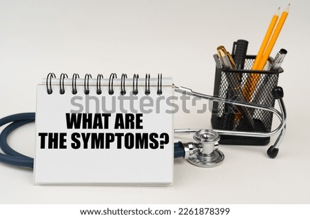 Medical concept. On the table are office supplies, a stethoscope and a notepad with the inscription - What are the symptoms