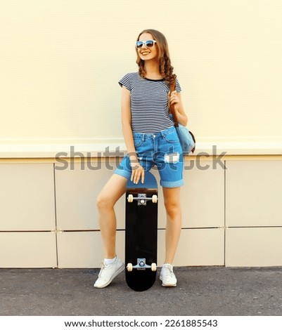 Portrait of cheerful young woman with skateboard in the city