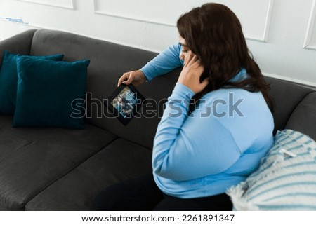 Rear view of a sad obese woman feeling heartbroken looking at the photo frame after a breakup with her boyfriend