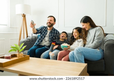 Excited parents and happy children laughing while watching kids movies together and eating popcorn Royalty-Free Stock Photo #2261892517