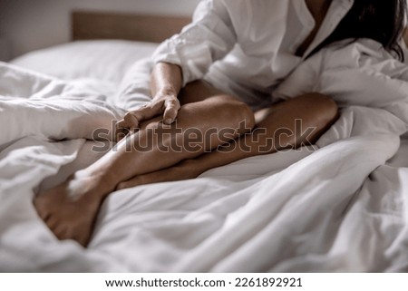 A young woman got severe cramps in her calf at night while sleeping. Royalty-Free Stock Photo #2261892921