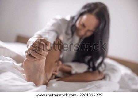 A young woman got severe cramps in her foot at night while sleeping. Royalty-Free Stock Photo #2261892929