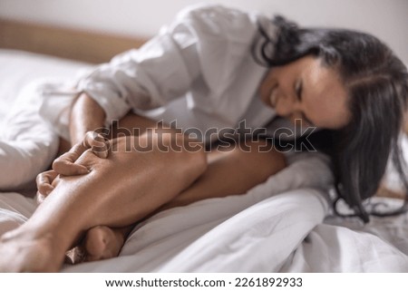 A young woman got severe cramps in her calf at night while sleeping. Royalty-Free Stock Photo #2261892933