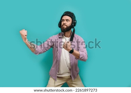 Funny angry man in a protective helmet wants to start a fight by putting out his fists. Isolated on a blue studio background.