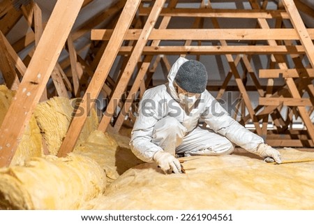 man insulates the roof and ceiling of the house with glass wool Royalty-Free Stock Photo #2261904561