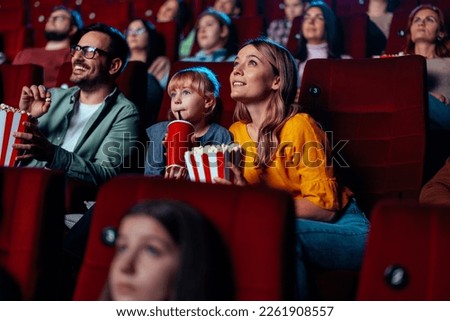 A young Caucasian family in in a movie theater watching a film together and having a good time. Royalty-Free Stock Photo #2261908557