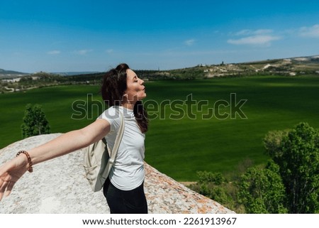 a sports woman with a backpack breathes air in nature