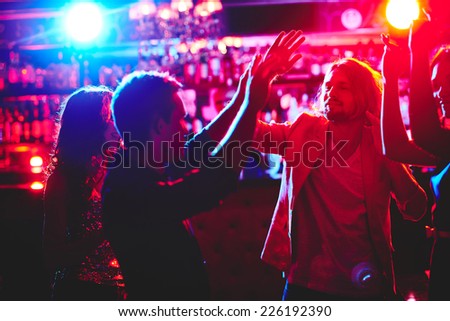 Group of happy friends dancing in nightclub