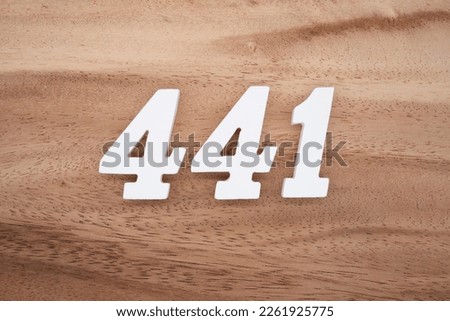 White number 441 on a brown and light brown wooden background. Royalty-Free Stock Photo #2261925775