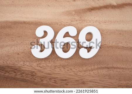 White number 369 on a brown and light brown wooden background.