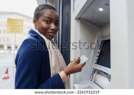 Young african woman withdrawing cash at the ATM