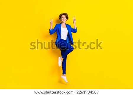 Full length photo of funny pretty lady dressed blue blazer jumping high showing two v-signs isolated yellow color background