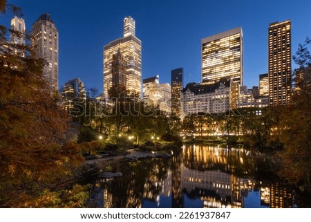 Illuminated Manhattan skyscrapers in evening and The Pond in Central Park. New York City